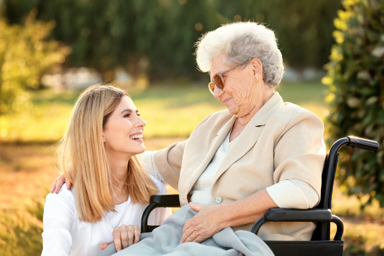 Senior woman in wheelchair and nurse from care home outdoors