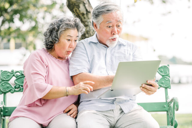 Asian couple feeling surprised using laptop