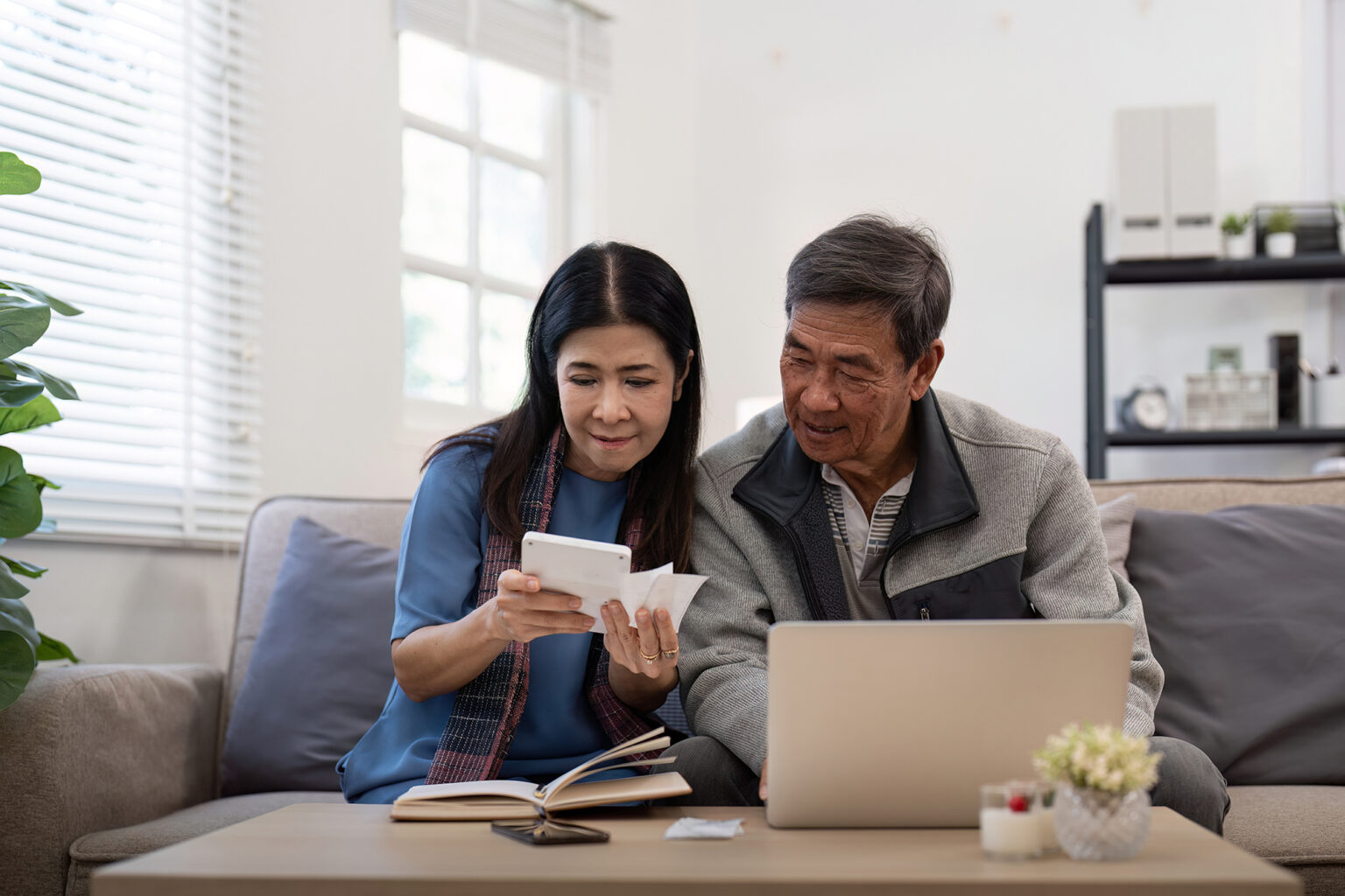 Asian senior couple checking and calculate financial bill together on sofa
