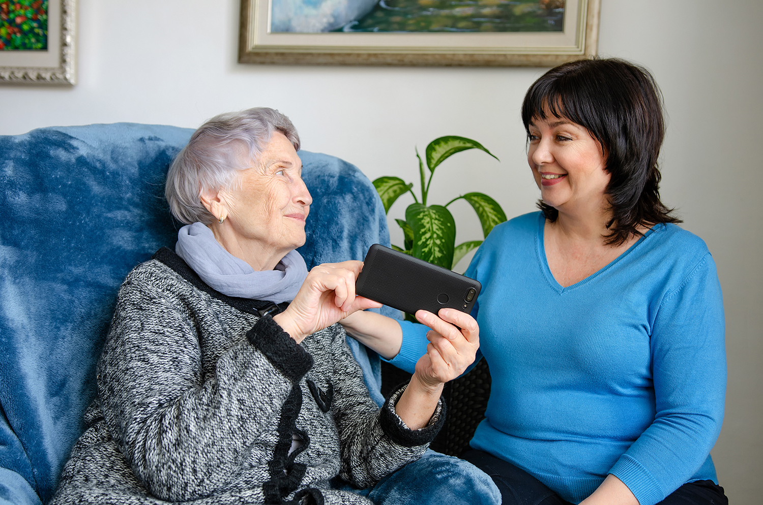 Cheerful female caregiver teaching an elderly woman how to use a
