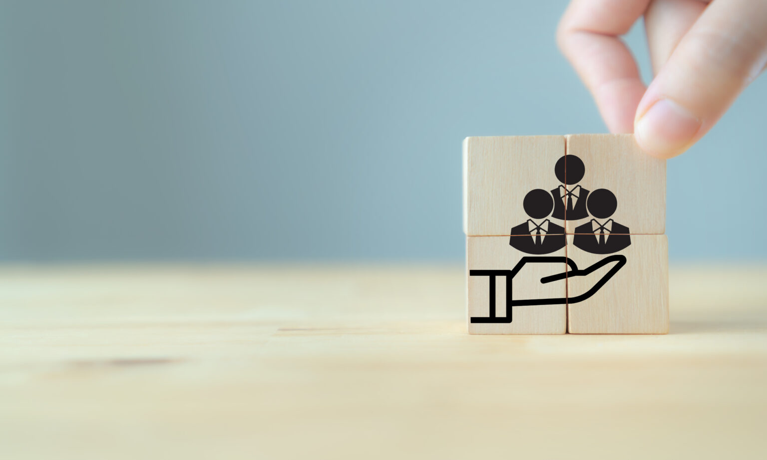 Wooden blocks with employee avatars being held in a hand