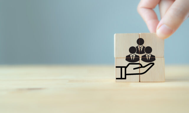 Wooden blocks with employee avatars being held in a hand