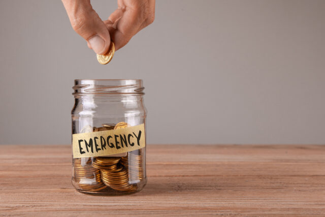 Emergency. Glass jar with coins and an inscription Emergency. Man holds  coin in his hand
