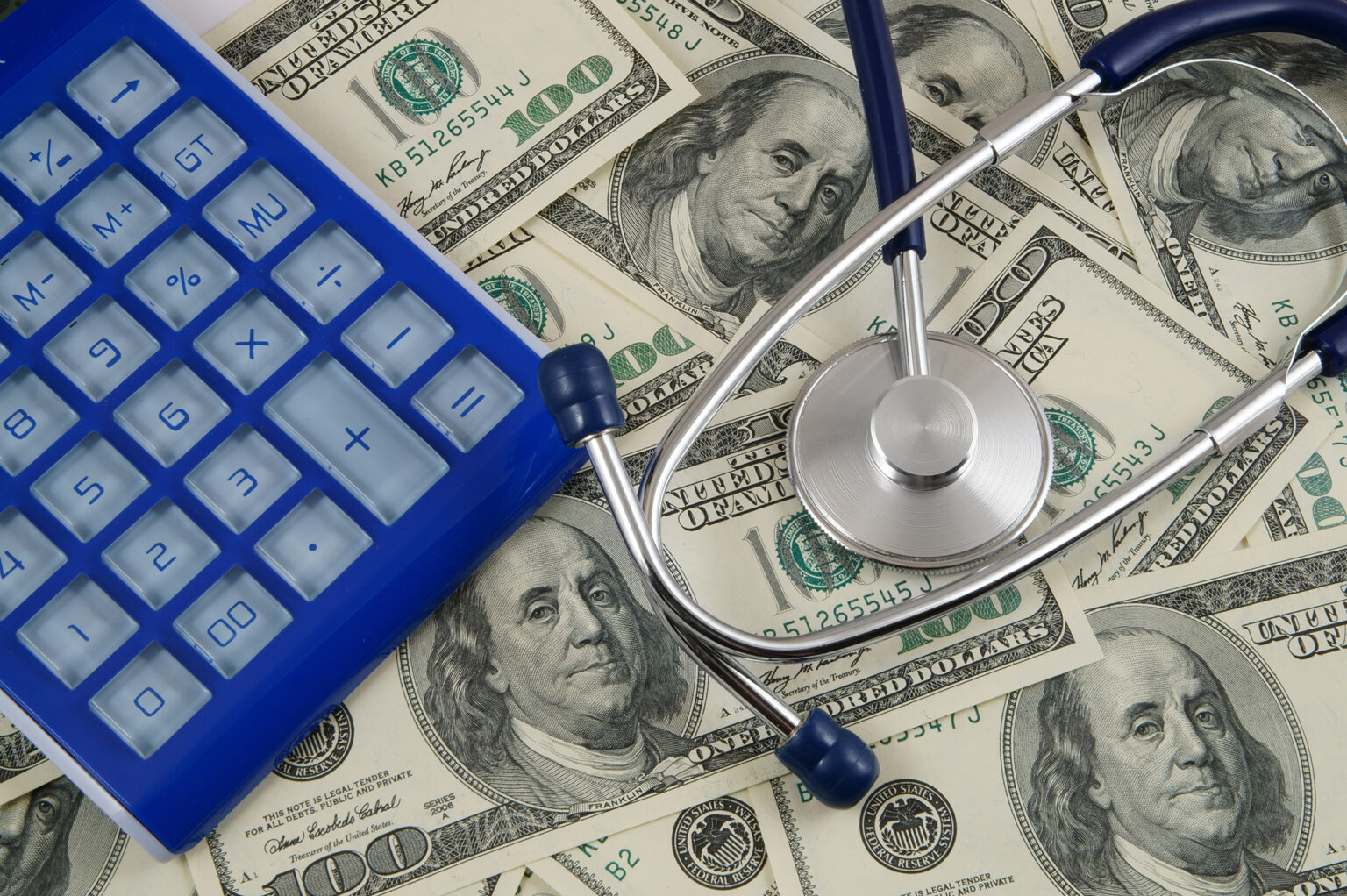 Blue calculator and stethoscope on money background