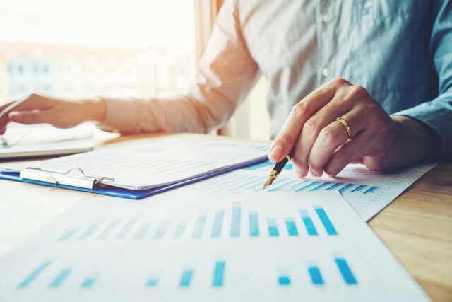 Close-up-of-hands-pointing-to-chart-on-a-desk