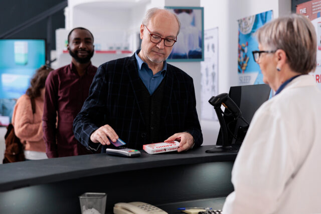 Senior person paying for medications with credit card at a pharmacy