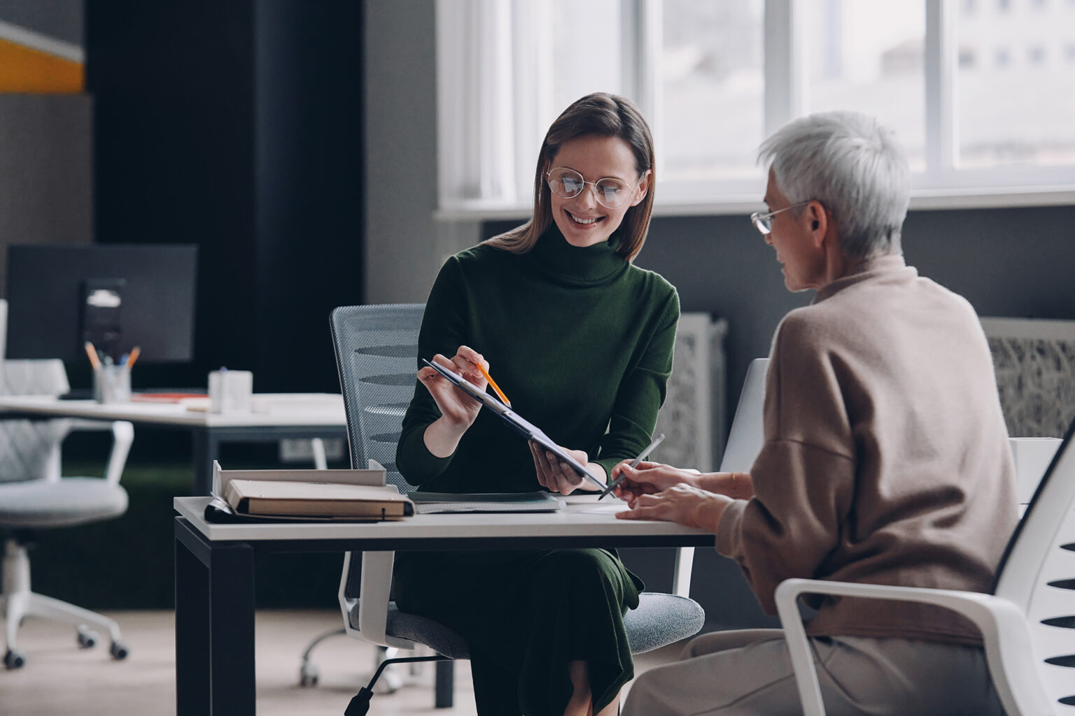 Senior woman discussing options with financial advisor while sitting in the office together