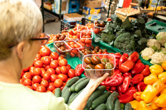 Top view of senior caucasian woman buying fresh organic vegetables and fruit at market place