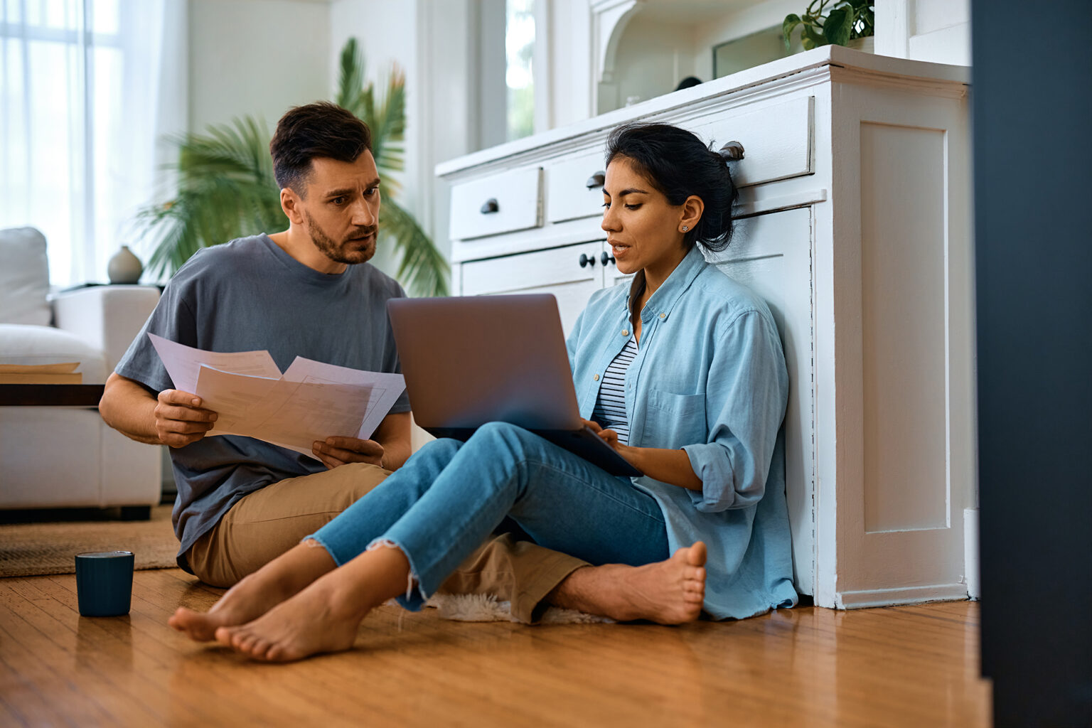Couple sitting on the floor looking at a laptop and documents