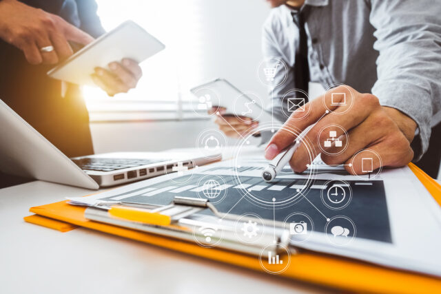 Two business people working at a desk with charts and infrastructure icons