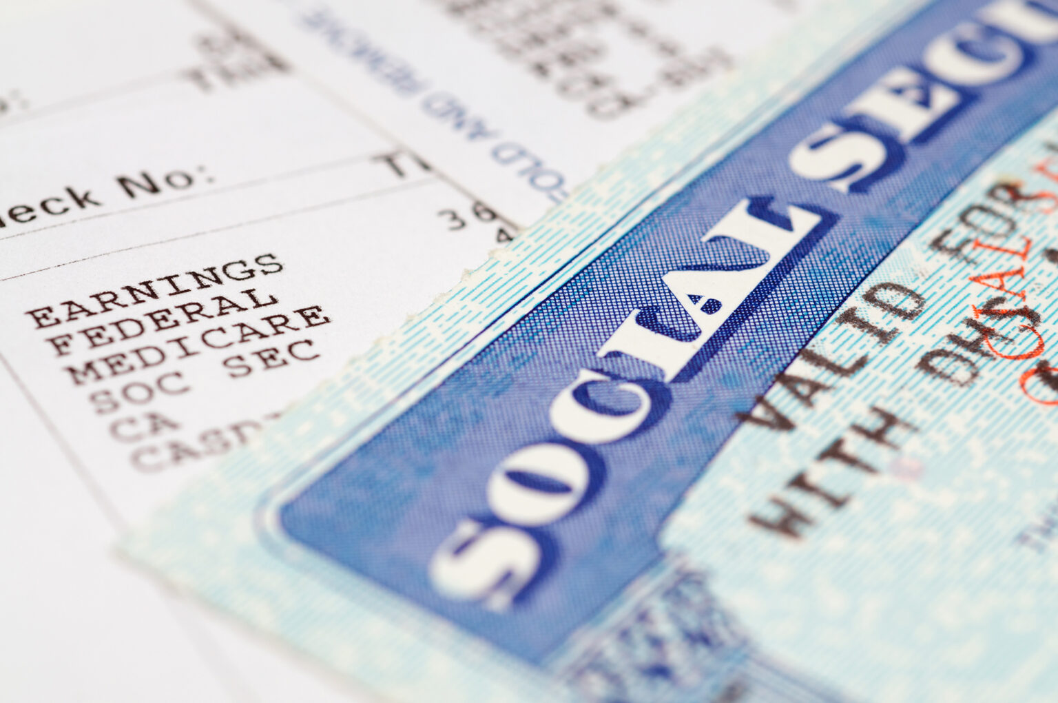 Social Security card on top of paystub showing federal tax deductions