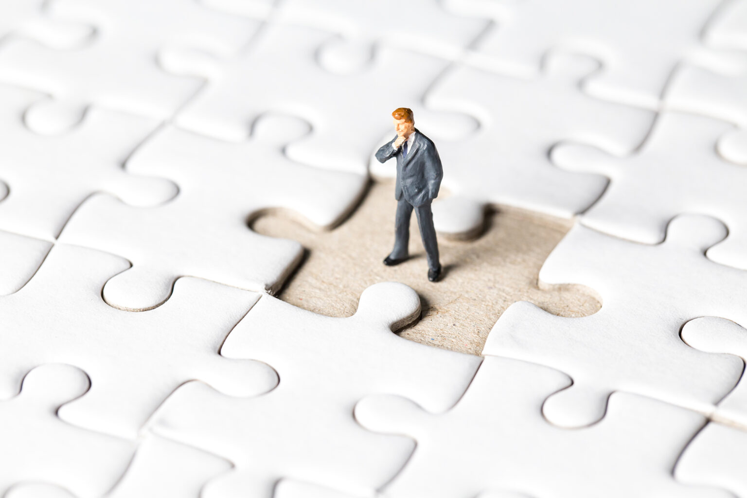 Miniature businessman stand on white jigsaw