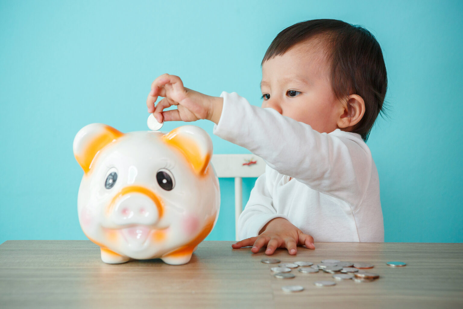 Young baby putting coin in a piggybank
