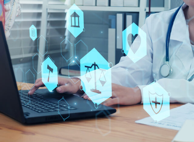 Doctor working on a laptop with healthcare graphics overlay