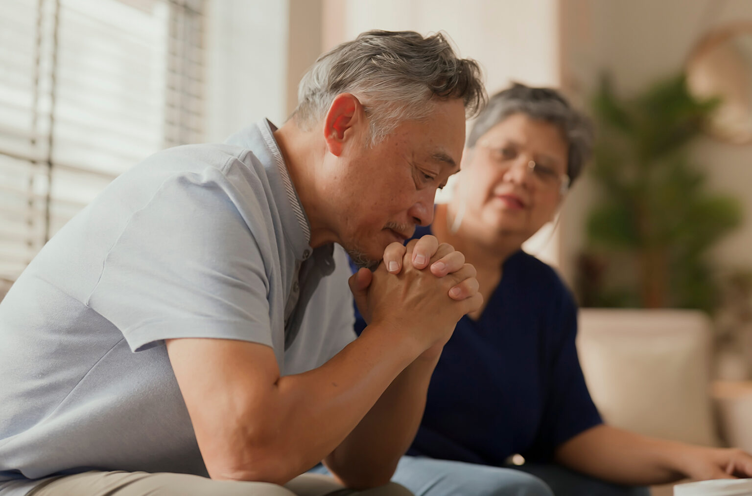 Older couple looking concerned sitting on a couch