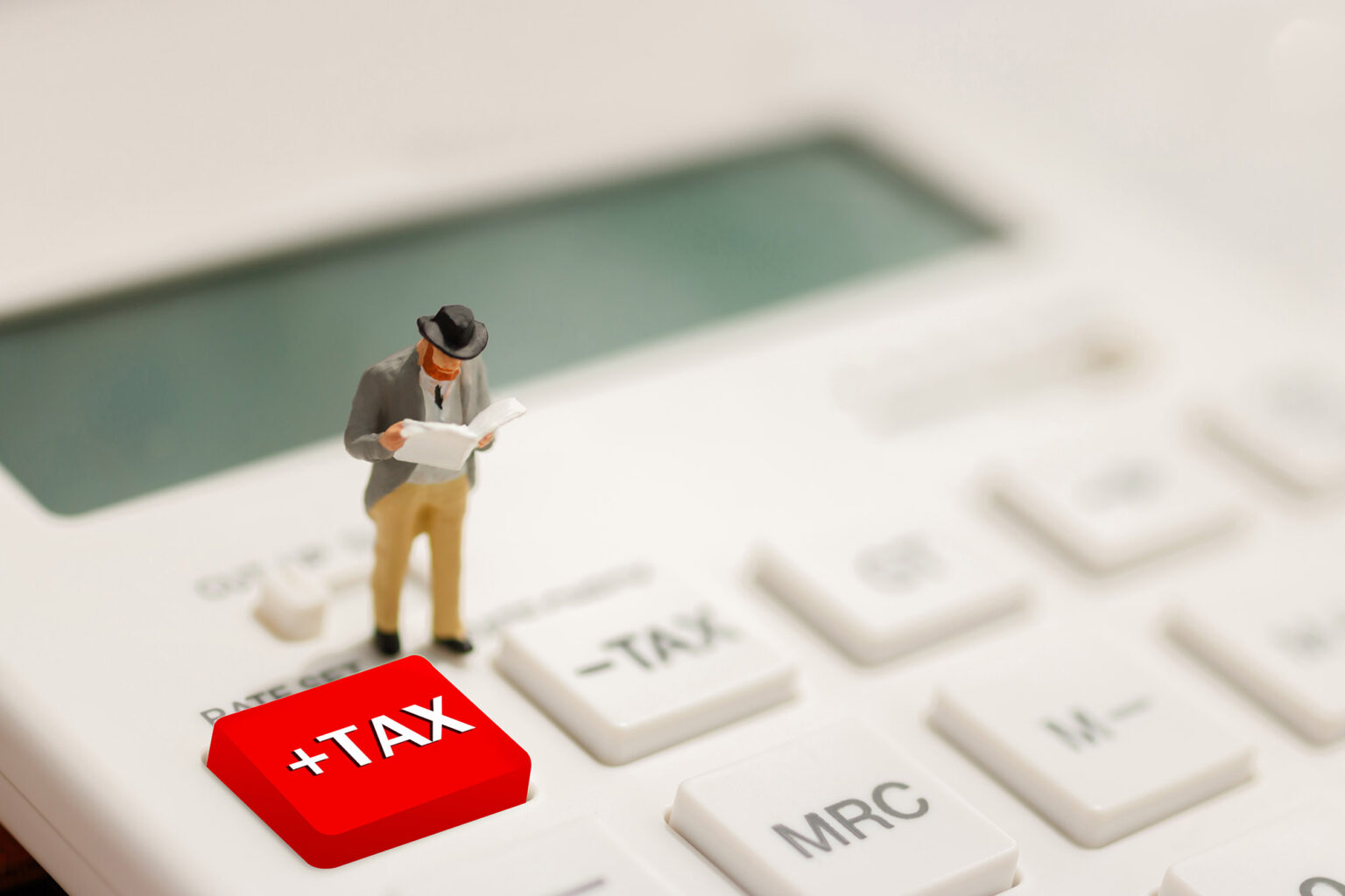 Tax Concept with miniature businessman reading on calculator