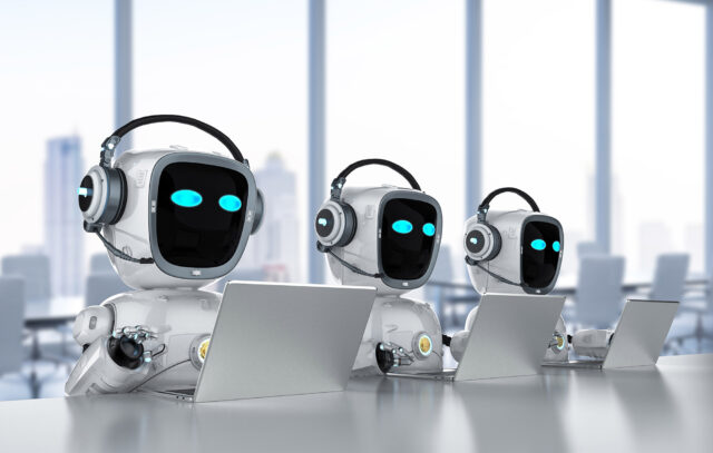Three robots working on laptops