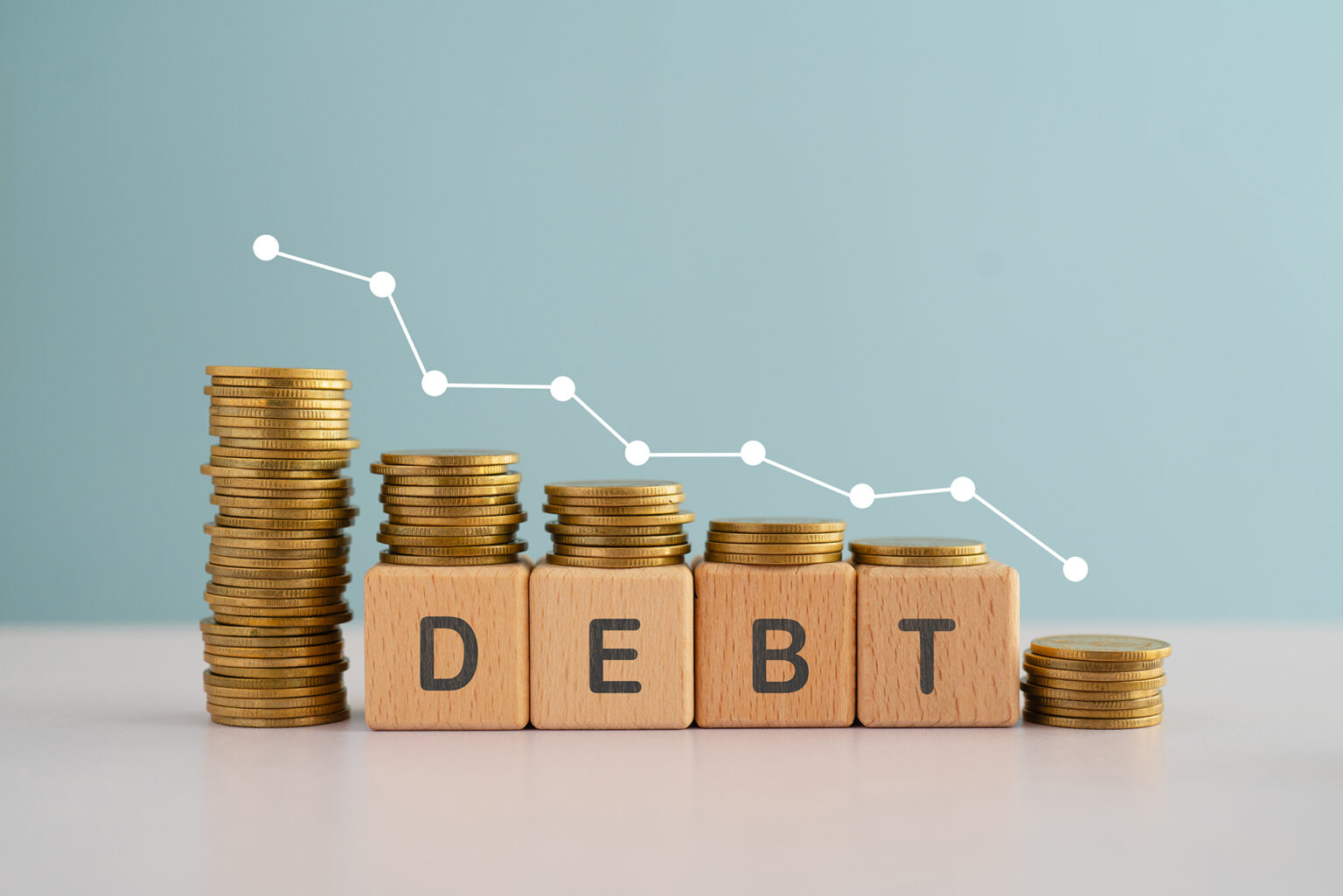 DEBT word on wooden cube blocks word and down arrow with stack of coins for financial debt decrease concept
