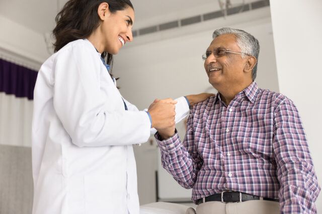 Young female doctor nurse medical professional hold hand on shoulder of older age male