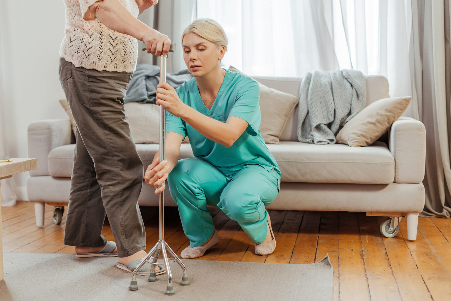Nurse adjusting walking cane for elderly woman at home