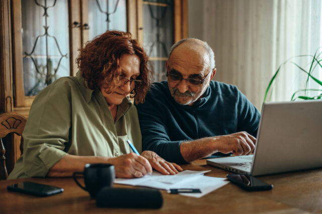 Senior couple using a laptop while doing their finances at home